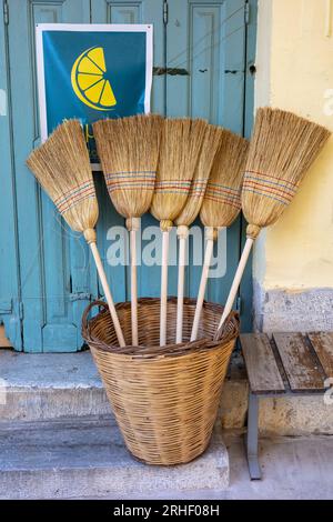 Traditional hand made brooms and a woven wicker baskest for sale on the street  In the bazaar district in the old quarter of Kalamata, Messinia, Pelop Stock Photo