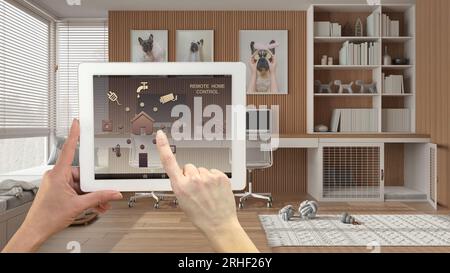 Smart remote home control system on a digital tablet. Device with app icons. Pet friendly home corner office, desk, dog bed with gate in the backgroun Stock Photo