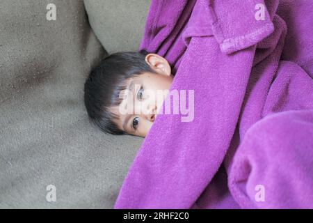 Sick child, child lying in bed, fully blanketed, having fever and sickness, health care Stock Photo