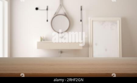 Empty wooden table, desk or shelf with blurred view of scandinavian white bathroom, washbasin with mirror and decors, modern interior design concept Stock Photo