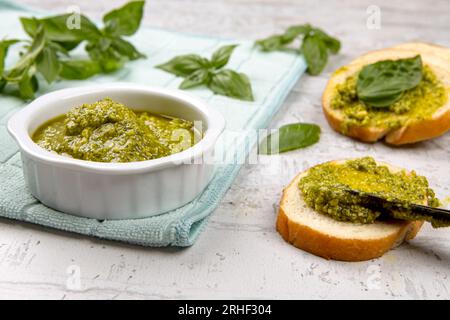 A photo of spreading fresh pesto on small slices of bread in a studio setting. Stock Photo