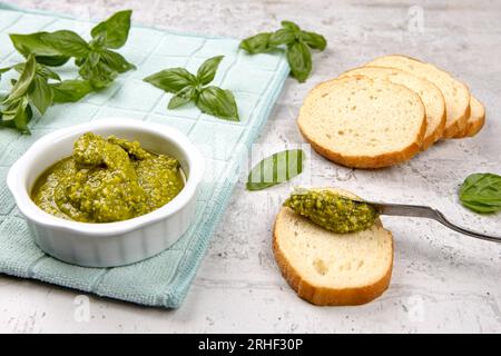 A photo of spreading fresh pesto on small slices of bread in a studio setting. Stock Photo