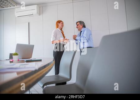 Two colleagues having conversation in office meeting room, age difference Stock Photo