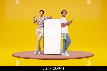 Man And Woman Leaning At Big Smartphone With Blank White Screen Stock Photo