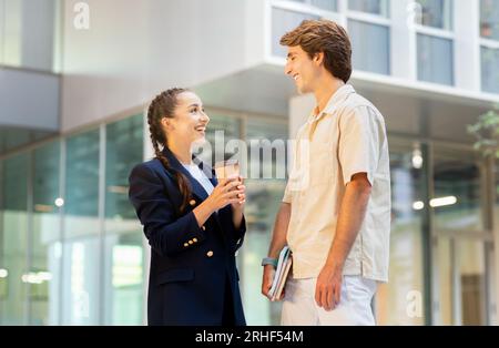 Happy young friends couple walking by street, talking and smiling Stock Photo