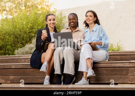 Three multicultural girlfriends students resting at university campus Stock Photo
