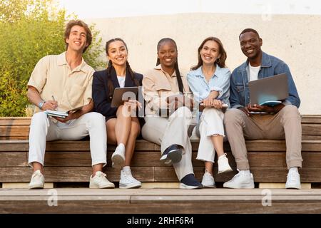 Portrait of happy multiethnic students posing at university campus Stock Photo
