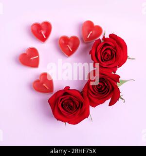 Romantic background with space for text. Red roses and candles in the shape of hearts. Love concept. Flat lay Stock Photo