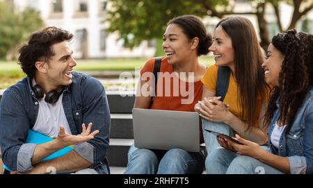 College Crush. Handsome Guy Talking To Group Of Happy Female Students Outdoors Stock Photo
