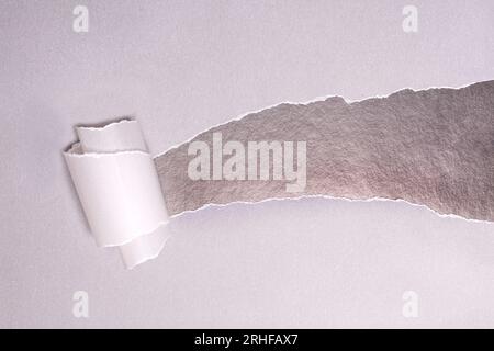 Torn paper with opening showing black background Stock Photo