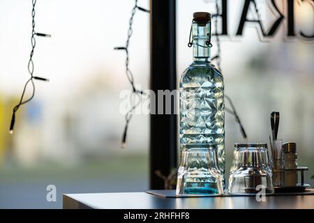 Cold fresh water in old-fashioned bottle with glasses on a cafe table. Stock Photo