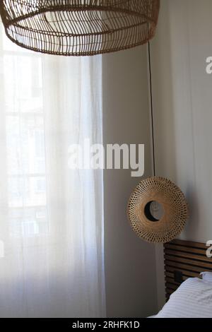 Tall window covered by sheer curtain with lighting fixtures hanging from a ceiling Stock Photo
