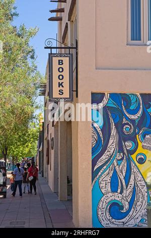 Sidewalk with pedestrians and book racks outside southwest style COAS Books building on Main street in downtown Las Cruces New Mexico Stock Photo