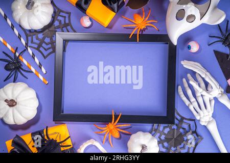 Happy Halloween holiday greeting card background. Flat lay gift boxes, set of Halloween symbols- spiders, bats, pumpkin, party decorations on purple b Stock Photo