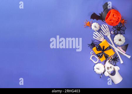 Happy Halloween holiday greeting card background. Flat lay gift boxes, set of Halloween symbols- spiders, bats, pumpkin, party decorations on purple b Stock Photo