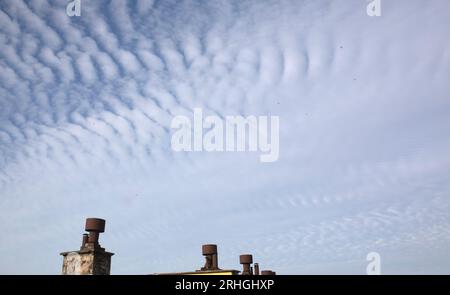 Clouds, Cirrocumulus or stratocumulus on the blue sky, above chimneys. Stock Photo