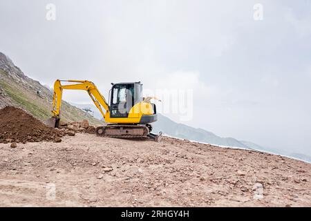 Excavator works in the highlands. Makes a trench for communications ...