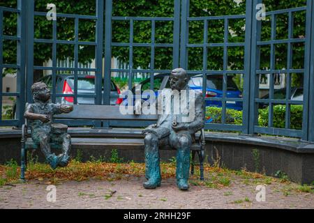 Das Denkmal zeigt Günther Grass, sitzend auf einer Bank, während neben ihm Oskar Matzerath, die zentrale Figur aus seinem berühmten Roman 'Die Blechtr Stock Photo