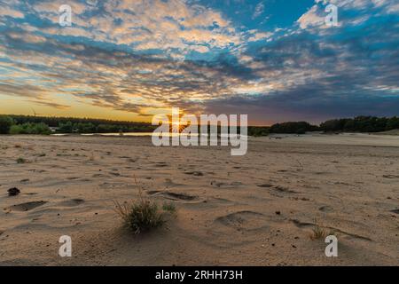 A dramatic and colourful sunset over the Lommelse Sahara, a National Park with sand dunes in Belgium with beautiful reflections in the lake of the clo Stock Photo