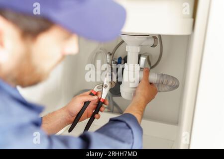 Close up of professional plumber installs a siphon pipe on the kitchen sink Stock Photo