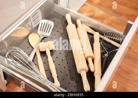 Kitchen utensil cutlery drawer organizer tray with simple set of tools, minimalist order. Open drawer with different utensils and folded towels. Order Stock Photo