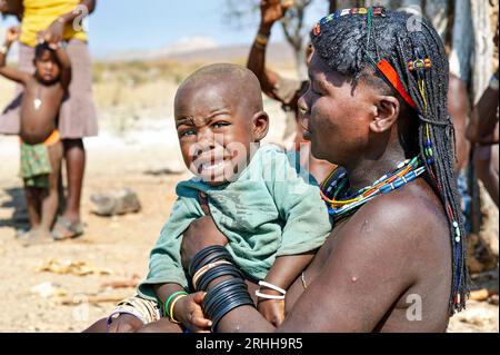Namibia. Portrait of a young woman of Zemba Bantu ethnic group with her crying child, in Kunene Region Stock Photo
