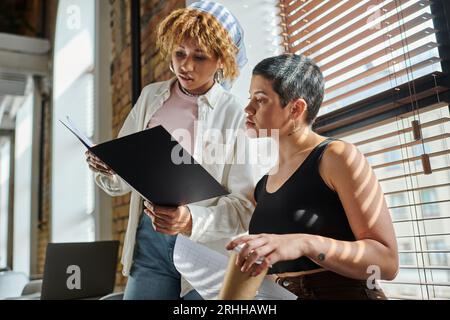 african american woman holding folder with documents, open space, startup project, ideas, colleagues Stock Photo