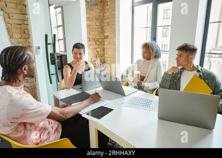 happy team leader talking to interracial colleagues, diversity, gadgets, discussing startup, ideas Stock Photo