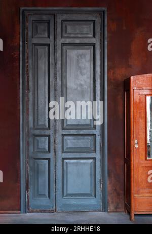 Vintage teal green wooden door on dark red exterior wall. Retro interior concept with copy space. Stock Photo
