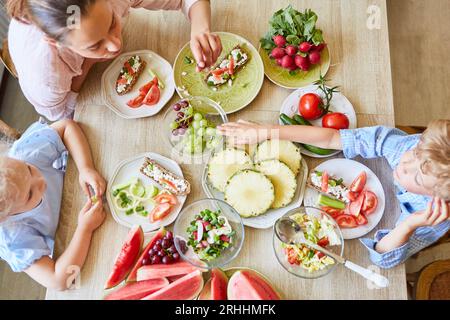 Son having fruits with mother and sister while sitting at home Stock Photo