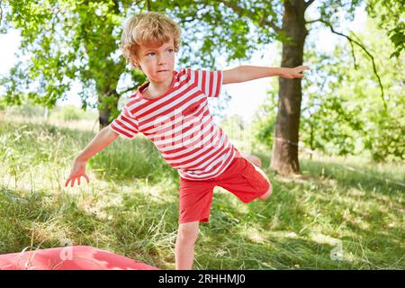 Blond boy looking away while balancing in garden Stock Photo