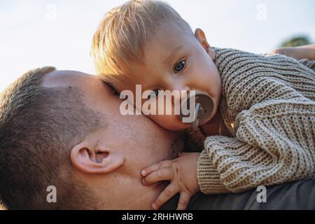 little baby boy on his dad's hands, sucking a pacifier. Spending time outdoors together. Father's day. High quality photo Stock Photo