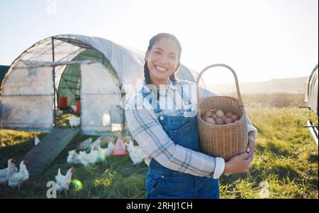 Happy woman with eggs in basket, farm and chickens on grass in sunshine countryside field with sustainable business. Agriculture, poultry farming and Stock Photo