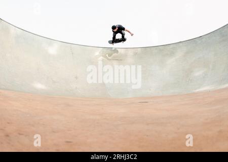 young man skateboarding at a skate park in the air wide angle minimal symmetrical Stock Photo