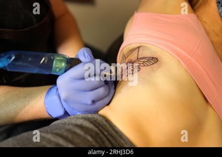 close up of wman getting tattooed on her side Stock Photo