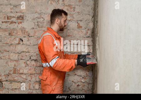 Man builder using straight level to check brick wall indoors. Stock Photo