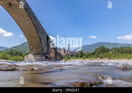 The water of the Trebbia river flows under the Gobbo bridge in Bobbio, Italy, on a hot summer day Stock Photo