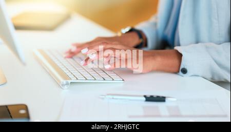 Closeup of a womans hands typing on a keyboard while sitting at a desk and sending an email in an office. Financial advisor doing online research for Stock Photo