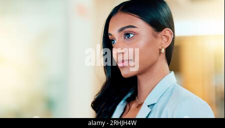 Business woman reading information on a computer screen while working in an office. Closeup on face of one confident young entrepreneur and focused Stock Photo