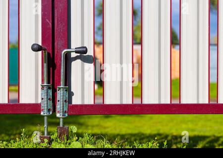 lower deadbolt on metal gates in the yard. locking mechanism on the gate Stock Photo