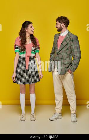 positive students looking at each other on yellow backdrop, happy man and woman in college outfits Stock Photo