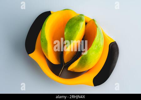 Coring a Fresh Mango with a Mango Corer: Overhead view of a cored mango isolated on a blue background Stock Photo