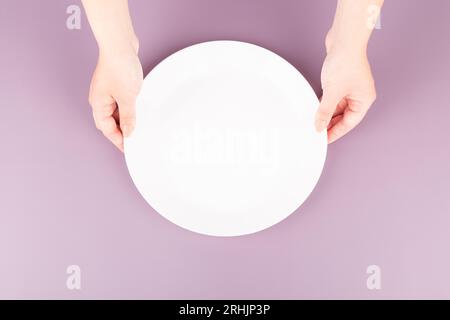 female hands displaying an empty plate in a zenithal view Stock Photo