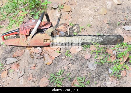 A portable gasoline Chainsaw put on the ground which is covered with a thin layer of the wood dust in a wild area Stock Photo