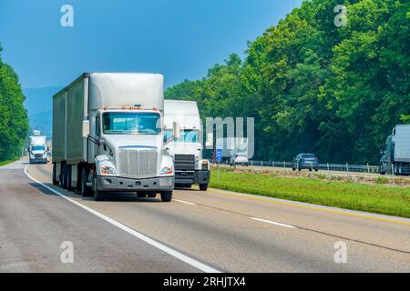Horizontal shot of three white semis on the interstate with copy space. Stock Photo