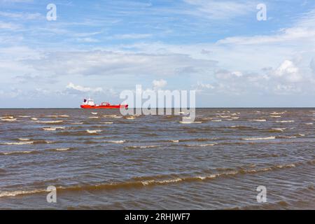 Red boat in the sea on a background of blue sky with clouds Stock Photo