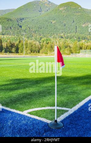 A Red flag at one corner of football stadium and soccer corner of a soccer field. Corner flag on green artificial grass. Empty football soccer field g Stock Photo