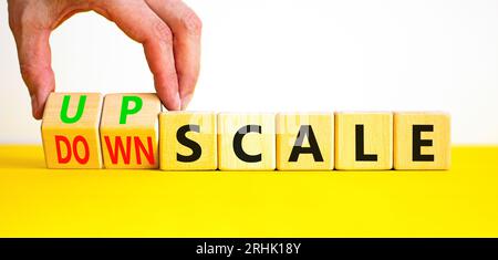 Upscale or downscale symbol. Concept words Upscale or Downscale on wooden cubes. Beautiful yellow table white background. Businessman hand. Business u Stock Photo