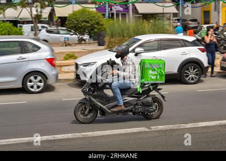 Sliema, Malta - 6 August 2023: Person riding a motor scooter with an Insulated container for the Bolt Food takeway delivery service on the back Stock Photo