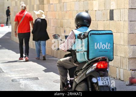 St Julians, Malta - 6 August 2023: Person riding a motor scooter with an Insulated container for the Wolt food takeway delivery service on the back Stock Photo